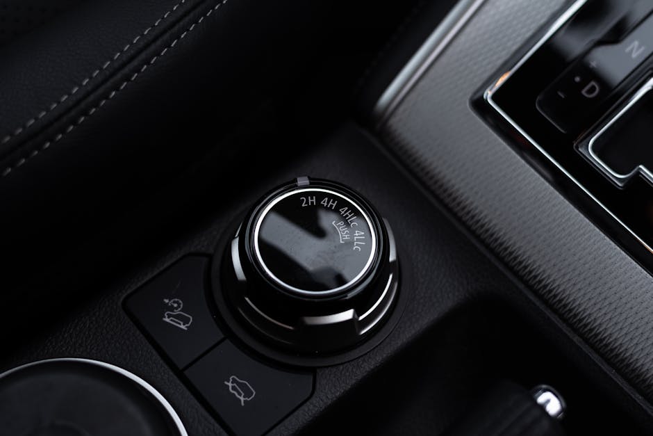 Detailed close-up of a car's gear shift and control knobs, showcasing modern vehicle technology.