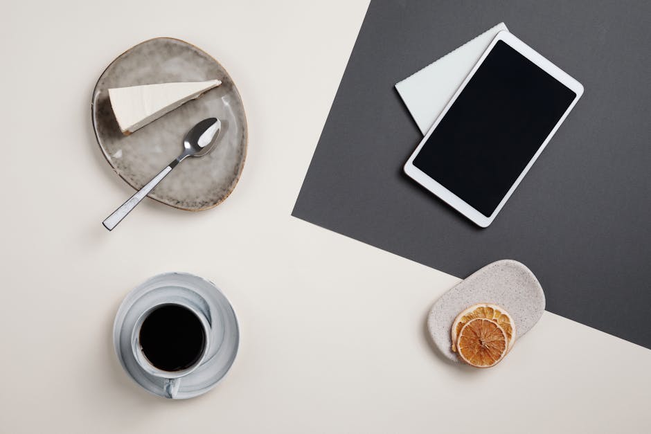 Minimalist flat lay featuring a dessert, coffee, tablet, and orange slices.