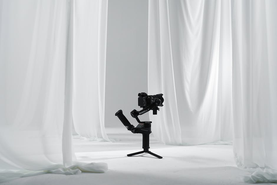 A professional camera on a gimbal in a minimalist white studio with curtains.