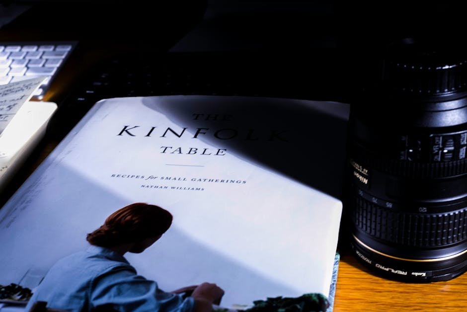 Artistic flat lay of a book and camera lens in dramatic light, perfect for creatives.