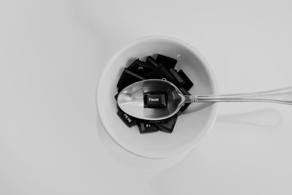 Unique black and white photo of keyboard keys in a bowl with a spoon featuring the 'Pause' key.