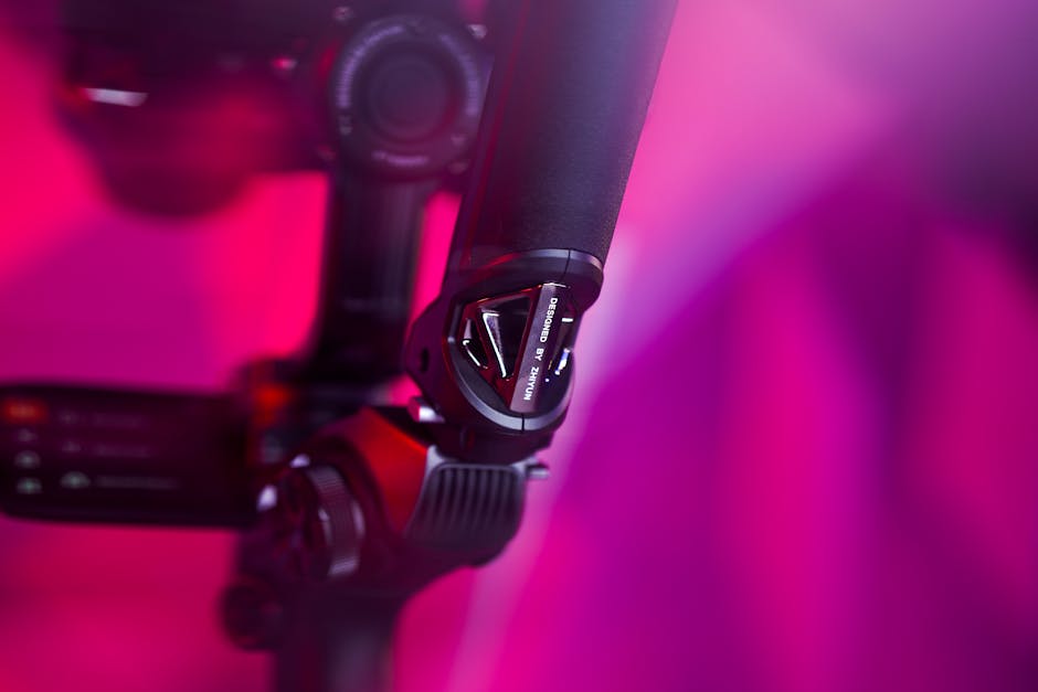 Macro shot of a camera gimbal against a vibrant pink background, showcasing modern technology.
