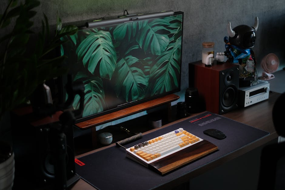 A sleek desk setup featuring technology accessories, a keyboard, and Monstera leaves for a modern touch.