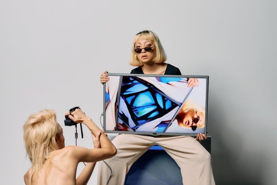Chic fashion model posing with monitor and camera for a modern editorial shoot.