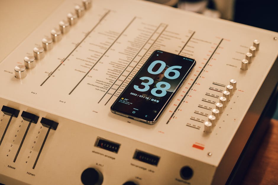 A smartphone showing time placed on a vintage audio mixer, captured indoors.