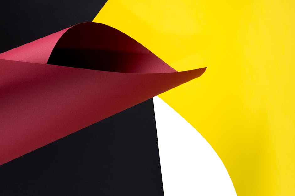 Abstract image featuring curved red, black, yellow, and white papers in a dynamic arrangement.