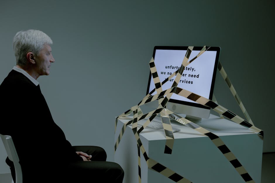 Elderly man confronted with job loss message on computer, symbolizing rejection.