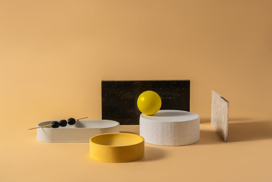 Flat lay of various minimalist concrete plates and decorative panels placed against yellow background
