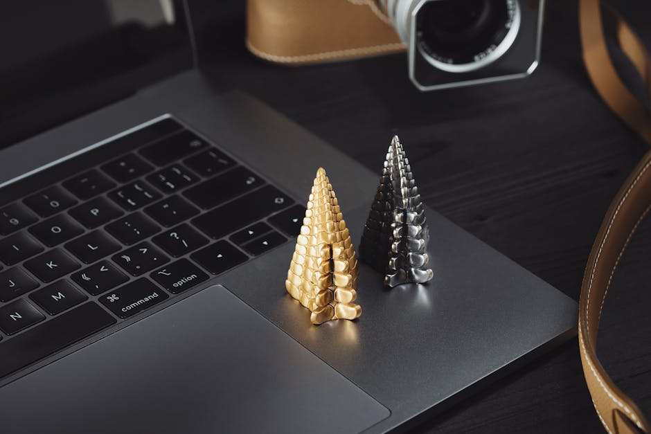 Stylish desktop setup featuring a gold and silver cone figurine on a laptop, perfect for modern workspace decor.