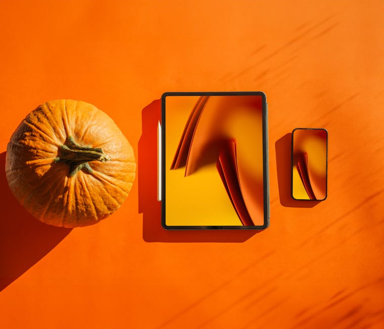 Tablet and smartphone set against an orange background next to a pumpkin.