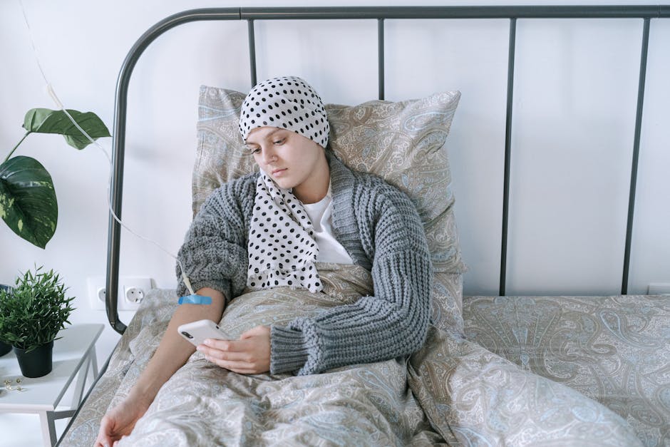 Woman undergoing cancer treatment at home, using a smartphone for support.
