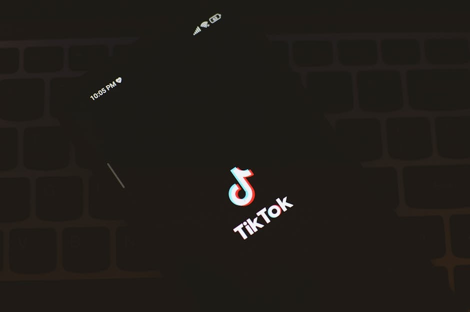 Close-up of a smartphone displaying the TikTok app logo against a dark keyboard background.