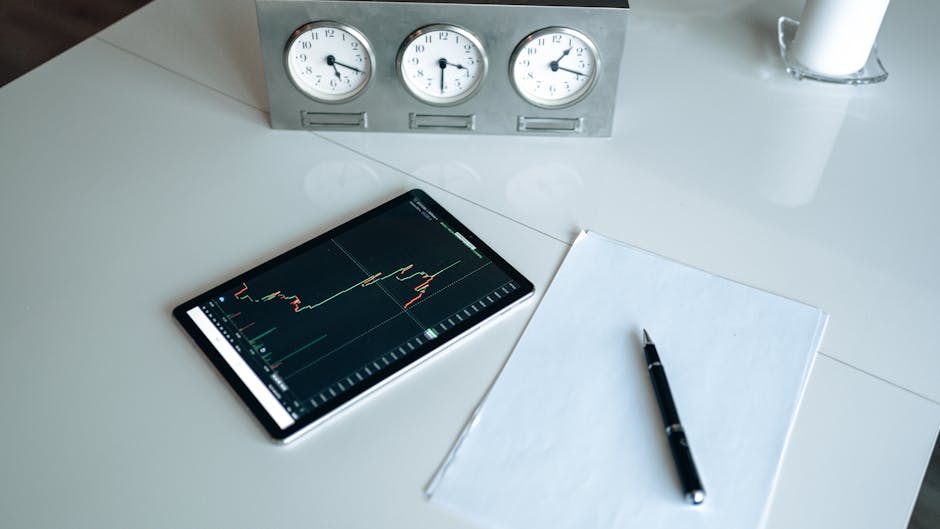 Tablet showing stock chart next to clocks and pen on desk. Perfect for business and finance themes.